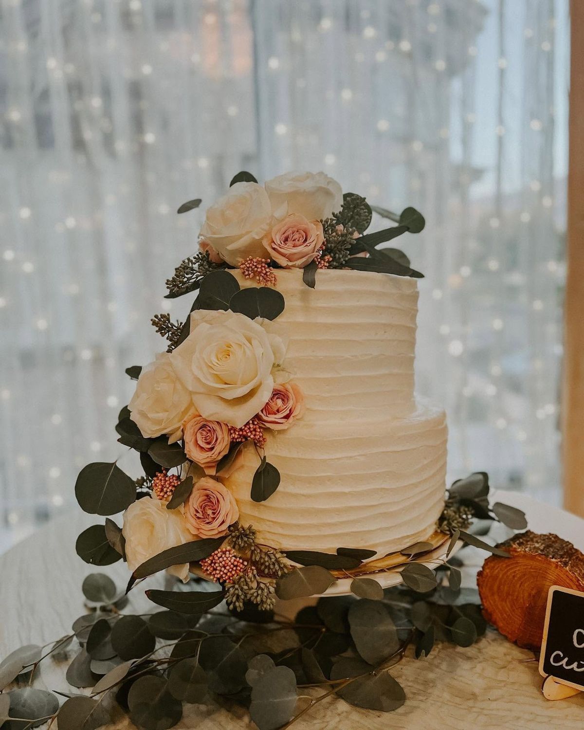 Wedding cake decorated with blush roses and greenery